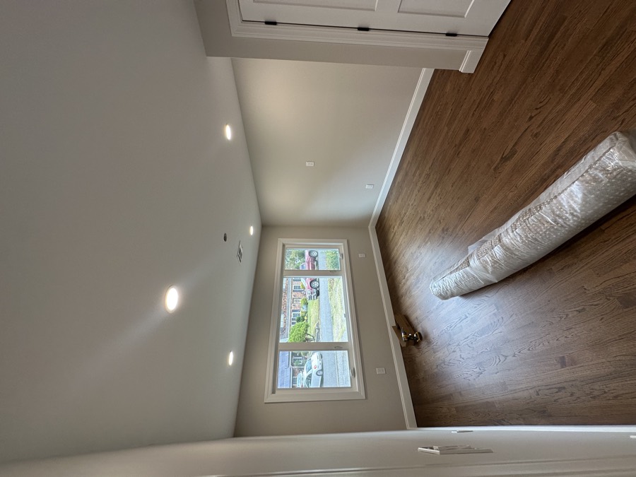 The same kind of room after a full renovation: new hardwood floors, fresh paint, new trim and recessed lighting.
